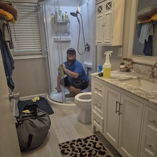 One of the Absolute Fresh cleaners scrubbing the inside of a glass shower